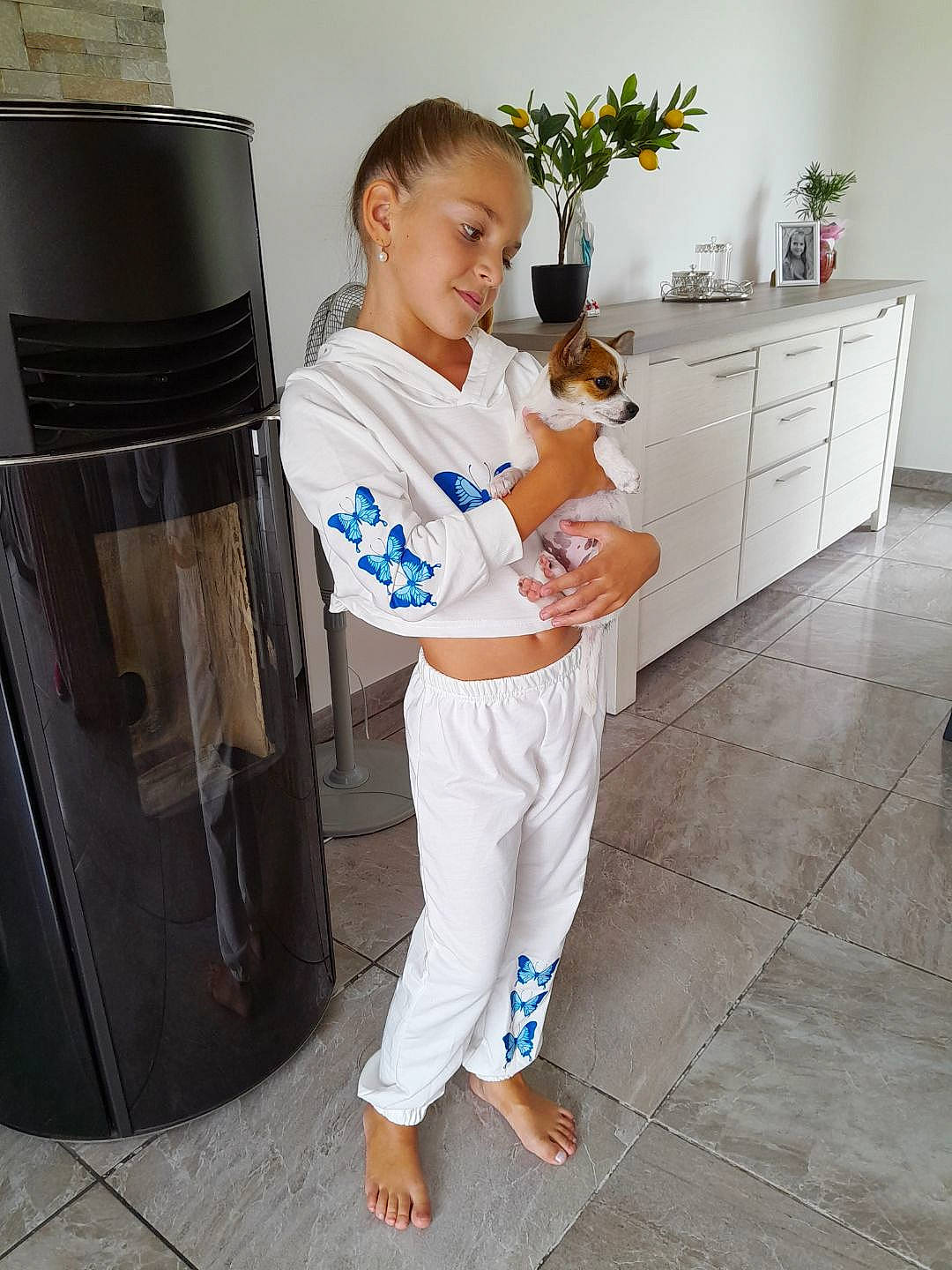 Shanna participe au concours pour gagner de l'argent avec cette photo : active_pants, cabinetry, companion_dog, fawn, flooring, flowerpot, houseplant, kitchen_appliance, knee, person, plant, room, sleeve, smile, standing, sweatpant, t_shirt, thigh, trunk, waist