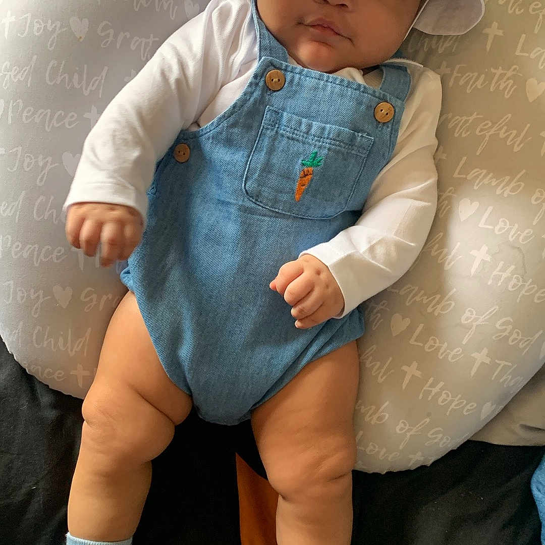 Loyalty joined the competition — help win amazing prizes! baby, bed, bucket_hat, carrot_patch, child, chubby_legs, cute, denim_overalls, hat, indoor, infant, looking_at_camera, pillow, portrait, relaxed, shoes, socks, soft_furniture, text_on_pillow, white_shirt