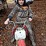 adventure, autumn, boots, camouflage_clothing, child, dirt_bike, dog, forest, hoodie, leaves, motorcycle, muddy, nature, outdoor, parked_car, pet, play, smiling, vehicle, young