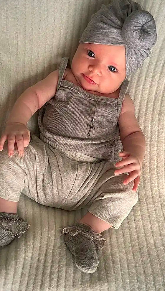 Charley participe au concours pour gagner de l'argent avec cette photo : baby, baby_toddler_clothing, cap, cheek, collar, comfort, doll, eye, finger, foot, grey, headwear, human_body, lip, pattern, person, skin, sleeve, textile, toddler