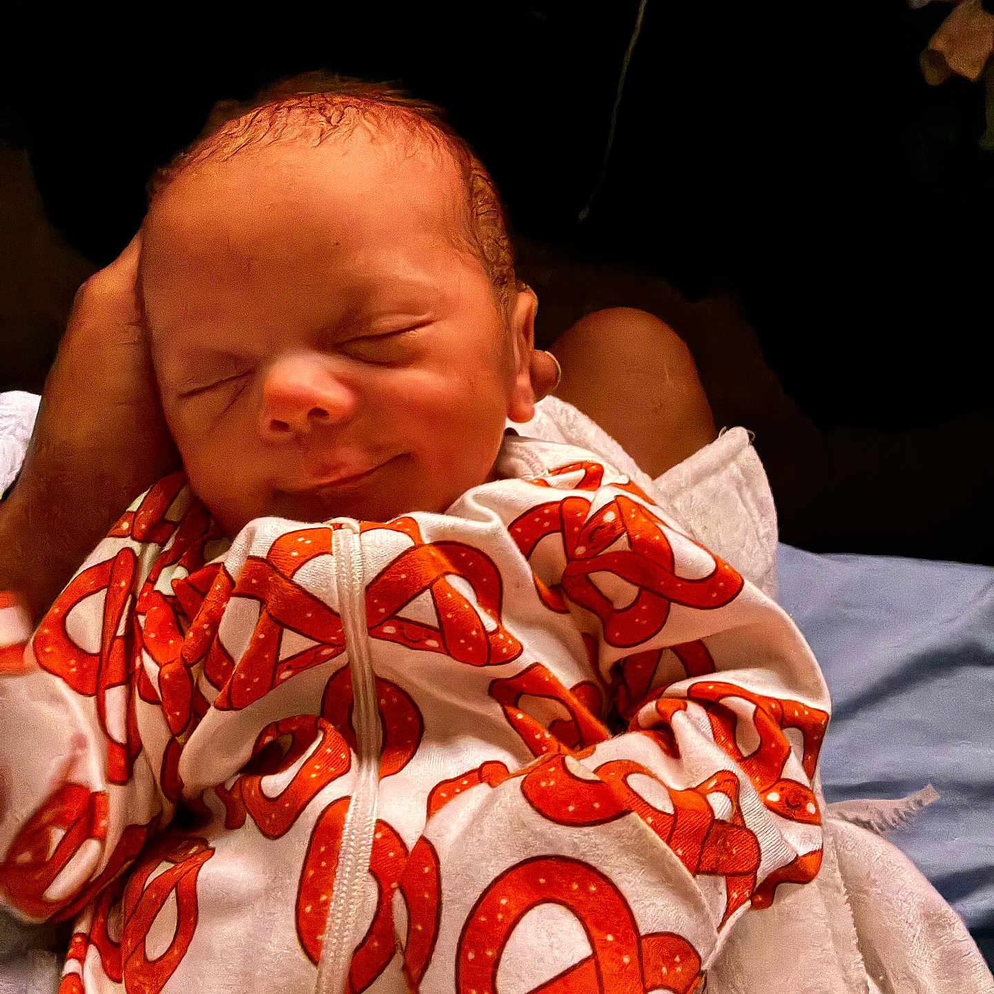 Terrell is registered to the contest to win money with this photo: newborn, baby, infant, sleeping, face, portrait, swaddled, blanket, white_clothing, orange_pattern, adult_hand, indoor, close_up, cozy, resting, head, eyes_closed, nose, mouth, family