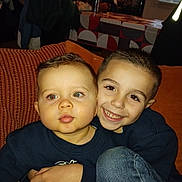 Marlone participe au concours pour gagner de l'argent avec cette photo : child, baby, toddler, brothers, siblings, smiling, couch, indoor, portrait, close_up, hug, family, denim, sweater, red_eye, living_room, pillow, couch_cushion, human_face, cozy