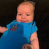 Za Kari is registered to the contest to win money with this photo: baby, smiling, blue_onesie, pacifier, cushion, infant, child, face, portrait, relaxing, indoor, happy, person, cute, young_child, head, skin, clothing, baby_girl, baby_boy