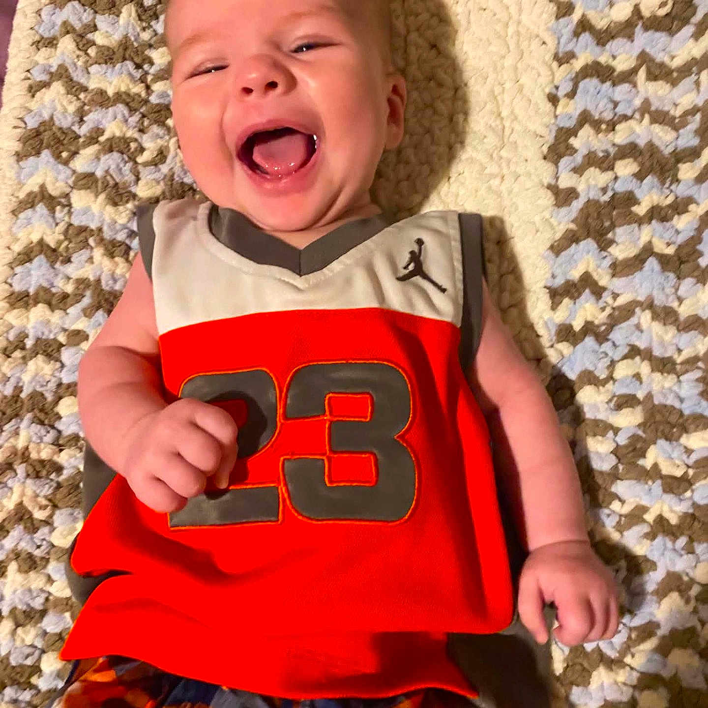 Za Kari joined the competition — help win amazing prizes! baby, infant, smiling, laughing, child, jersey, number_23, plaid_shorts, blanket, knitted, happy, cute, portrait, lying_down, indoor, skin, face, hand, clothing, colorful