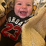 apparel, baby, black_tshirt, blanket, cheerful, child, closeup, clothing, cozy, cute, face, happy, indoors, infant, jordan_jersey, portrait, smiling, soft_texture, warm, young