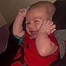 Za Kari is registered to the contest to win money with this photo: baby, infant, smiling, red_onesie, pacifier, arms_up, happy, cute, young_child, portrait, indoors, blanket, cozy, sleepwear, head, face, skin, person, lying_down, child
