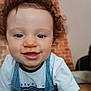 Gabriel a rejoint le concours — aidez-le/la à gagner de superbes lots ! toddler, child, curly_hair, smiling, blue_eyes, denim_overalls, white_tshirt, close_up, indoor, brick_wall, happy, person, cute, face, portrait, baby, young_child, curiosity, soft_focus, background_blur