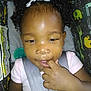 Honesty is registered to the contest to win money with this photo: toddler, child, car_seat, curly_hair, hair_bows, finger_sucking, seatbelt, pink_shirt, indoor, baby, cute, face, person, portrait, animal_print, colorful, sitting, young_child, looking_down, closeup
