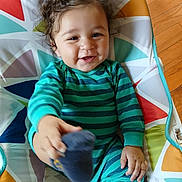 Mesiyah joined the competition — help win amazing prizes! baby, child, closeup, colorful_cushion, curly_hair, cute, flooring, foot, hand, happy, indoor, infant, patterned_fabric, person, playful, portrait, smiling, sock, striped_clothing, wood_floor
