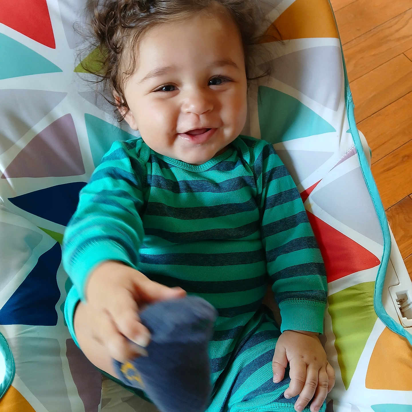 Mesiyah joined the competition — help win amazing prizes! baby, child, closeup, colorful_cushion, curly_hair, cute, flooring, foot, hand, happy, indoor, infant, patterned_fabric, person, playful, portrait, smiling, sock, striped_clothing, wood_floor