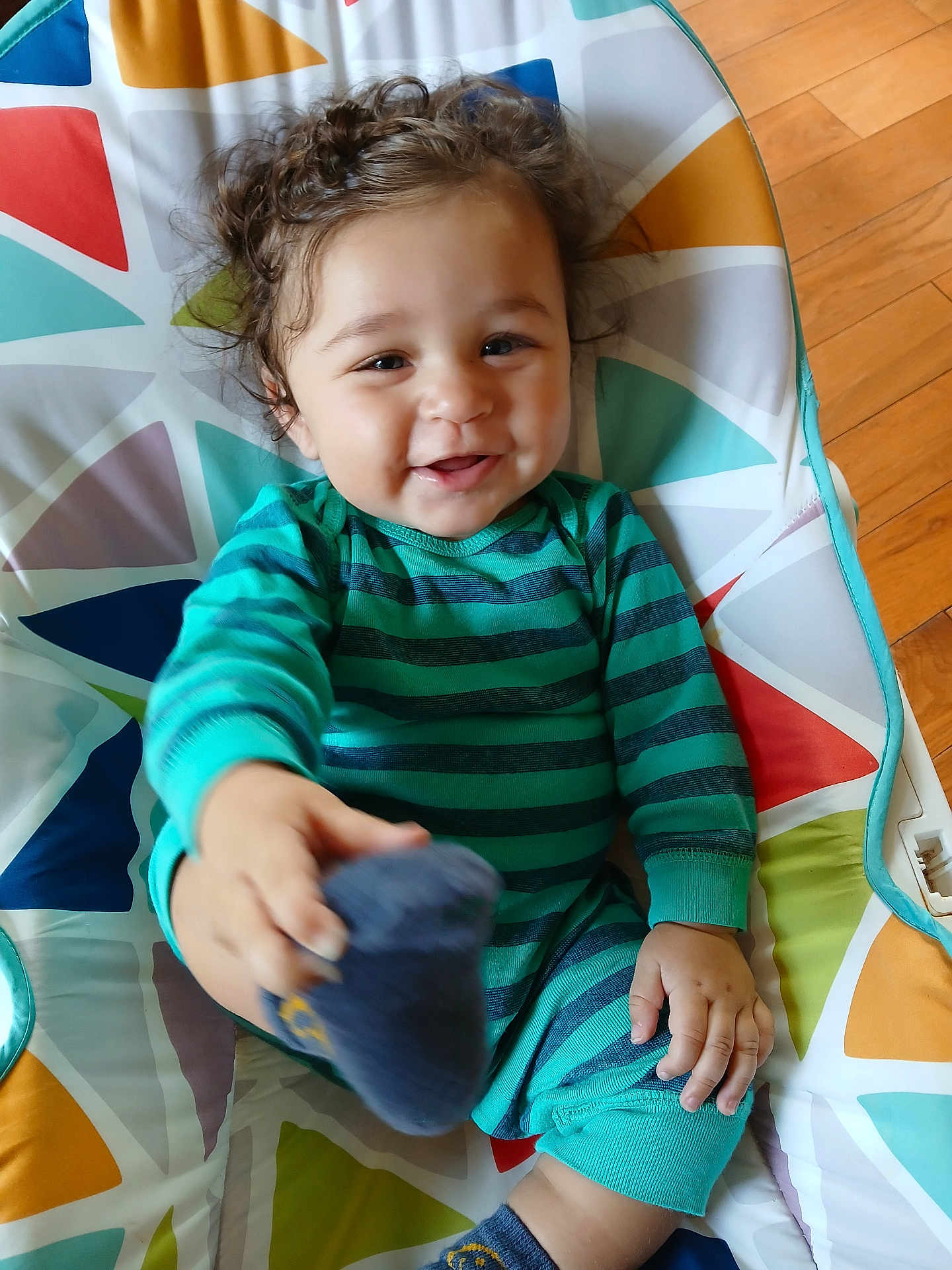 Mesiyah joined the competition — help win amazing prizes! baby, child, closeup, colorful_cushion, curly_hair, cute, flooring, foot, hand, happy, indoor, infant, patterned_fabric, person, playful, portrait, smiling, sock, striped_clothing, wood_floor