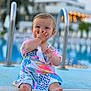 Iyla-Grace is registered to the contest to win money with this photo: baby, child, poolside, dress, colorful_clothing, blue_eyes, sitting, hand_on_face, outdoor, daylight, water, blurred_background, playful, cute, infant, barefoot, summer, holiday, resort, smiling