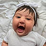 baby, infant, smiling, headband, white_clothing, cute, happy, portrait, face, child, lying_down, soft_texture, blanket, indoors, skin, hair, mouth_open, cheeks, expression, person