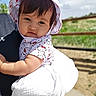 baby, child, face, hat, hello_kitty, outdoor, greenery, sunny_day, cute, smile, person, clothing, infant, nature, portrait, white_blanket, holding, headwear, toddler, daylight
