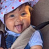 baby, child, smiling, tongue_out, hat, sunhat, cherry_pattern, denim_overalls, car_seat, seatbelt, cute, happy, infant, chubby_cheeks, outdoor_light, playful, portrait, sitting, clothing, young_child
