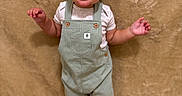 Josiah is registered to the contest to win money with this photo: baby, toddler, child, standing, overalls, striped_clothing, cactus_patch, white_shirt, barefoot, carpet, beige_background, smiling, portrait, indoors, cute, happy, face, head, skin, person
