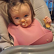 Chelby participe au concours pour gagner de l'argent avec cette photo : baby, toddler, child, highchair, bib, food, messy, pigtails, smiling, eating, face, blue_eyes, tray, cheeky_expression, hand, indoor, furniture, window, cookie, crumbs
