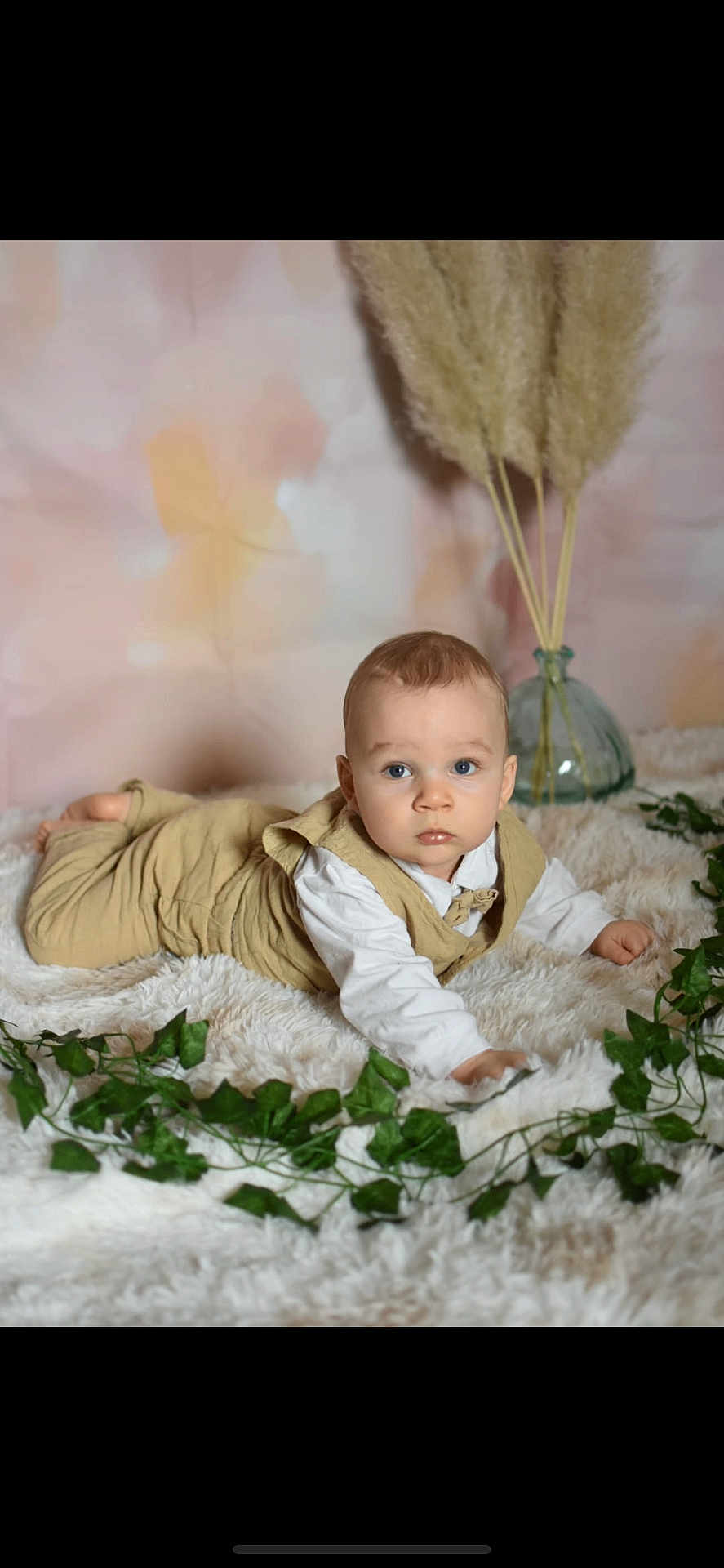 Naël a rejoint le concours — aidez-le/la à gagner de superbes lots ! baby, child, infant, blue_eyes, fluffy_rug, green_leaves, pampas_grass, glass_vase, pastel_background, white_clothing, beige_overall, portrait, indoor, cute, curious, crawling, soft_texture, decor, young, person