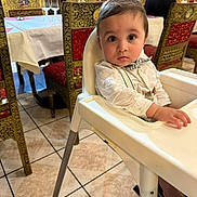 Viaansh participe au concours pour gagner de l'argent avec cette photo : baby, child, high_chair, restaurant, table, chair, floor, person, clothing, bow_tie, face, eyes, hand, tile_floor, waiter, interior, dining, decor, furniture, sitting