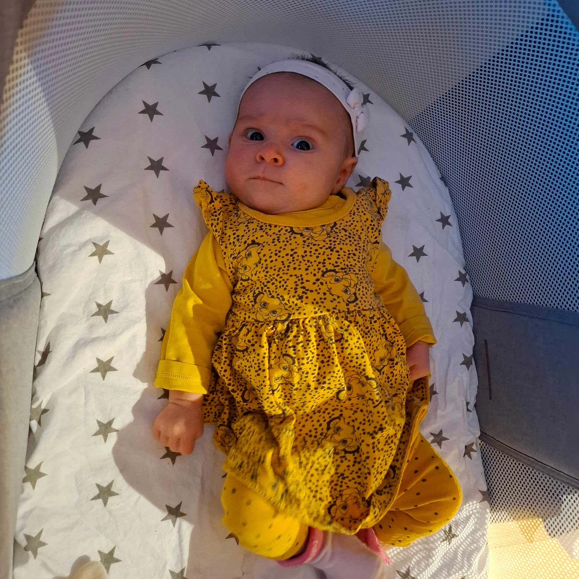 Mya participe au concours pour gagner de l'argent avec cette photo : baby, infant, yellow_clothing, headband, playpen, mattress, stars_pattern, lying_down, indoors, cute, child, one_person, looking_at_camera, soft_lighting, small_hands, expression, casual, cozy, comfortable, baby_girl