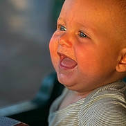 Colt joined the competition — help win amazing prizes! baby, infant, child, smile, laughing, blue_eyes, chubby_cheeks, drool, open_mouth, close_up, portrait, striped_shirt, onesie, golden_hour, sunlight, warm_tone, bokeh, blurred_background, highchair, happy