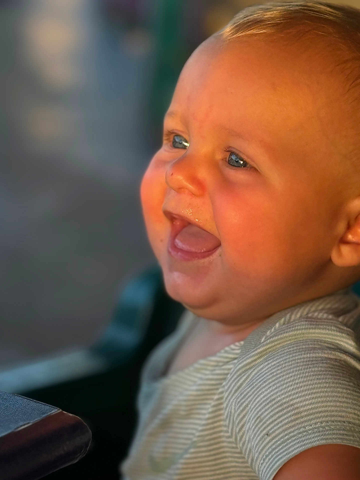 Colt joined the competition — help win amazing prizes! baby, infant, child, smile, laughing, blue_eyes, chubby_cheeks, drool, open_mouth, close_up, portrait, striped_shirt, onesie, golden_hour, sunlight, warm_tone, bokeh, blurred_background, highchair, happy