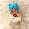 baby, infant, blue_bow, headband, white_clothing, blanket, heart_pattern, cute, soft_texture, portrait, newborn, child, lying_down, cozy, expression, hand, small, indoors, warm, adorable