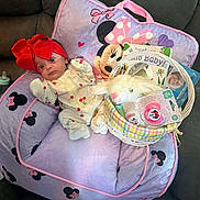 Dai'Lani is registered to the contest to win money with this photo: baby, red_bow, purple_cushion, minnie_mouse, plush_bunny, pacifier, basket, onesie, couch, baby_book, infant, wide_eyes, cute, child, indoor, soft_toys, pink, yellow, white, comfortable