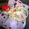 baby, red_bow, purple_cushion, minnie_mouse, plush_bunny, pacifier, basket, onesie, couch, baby_book, infant, wide_eyes, cute, child, indoor, soft_toys, pink, yellow, white, comfortable