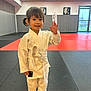 child, judo, martial_arts, dojo, karate_gi, white_belt, barefoot, smile, waving, indoor, sport, young_child, training, mat, portrait, cute, happy, person, activity, gym