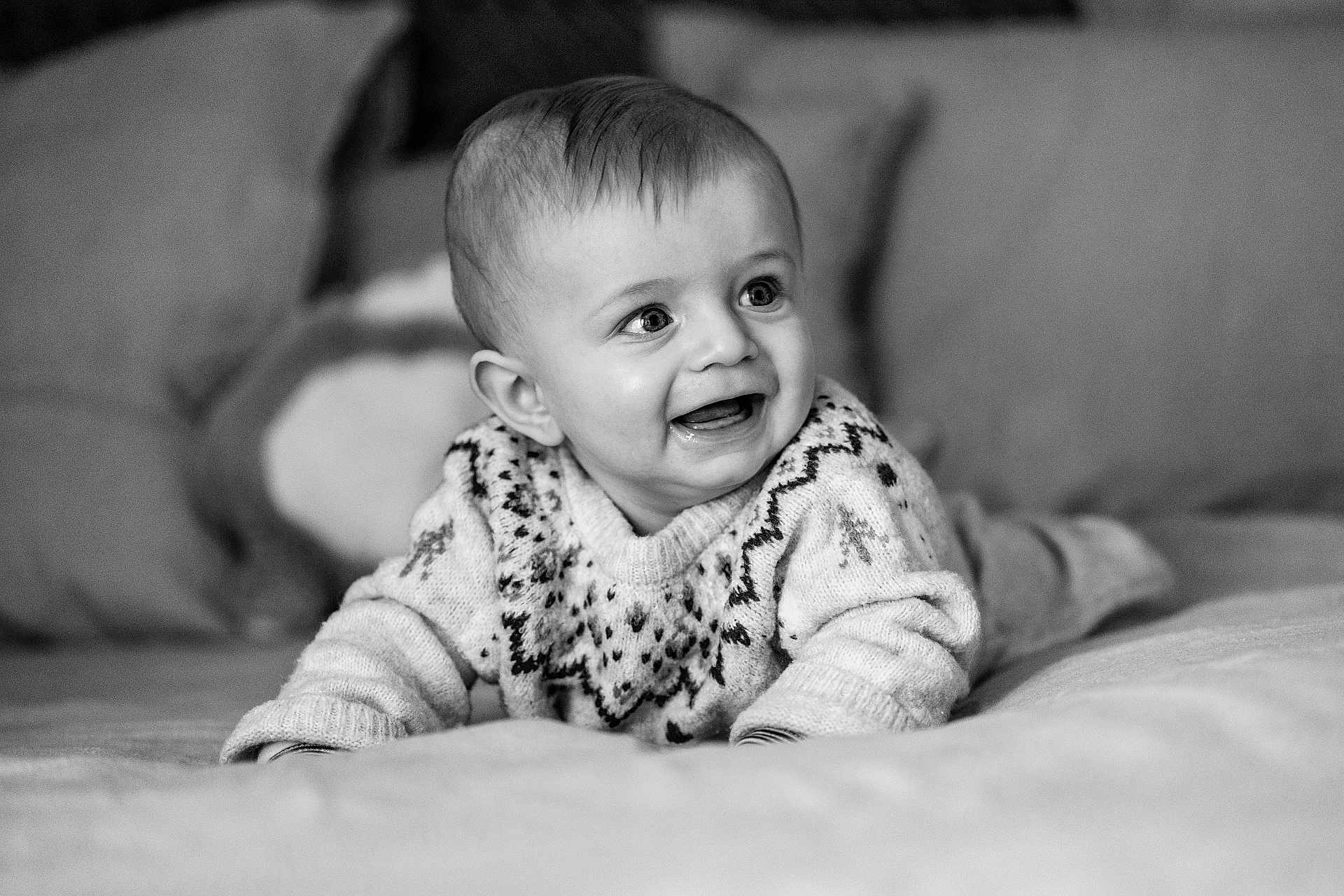 Zack participe au concours pour gagner de l'argent avec cette photo : baby, child, smiling, sweater, patterned_clothing, lying_down, soft_surface, indoor, portrait, black_and_white, happy, cute, infant, young_child, face, eyes, mouth, expression, cozy, warm