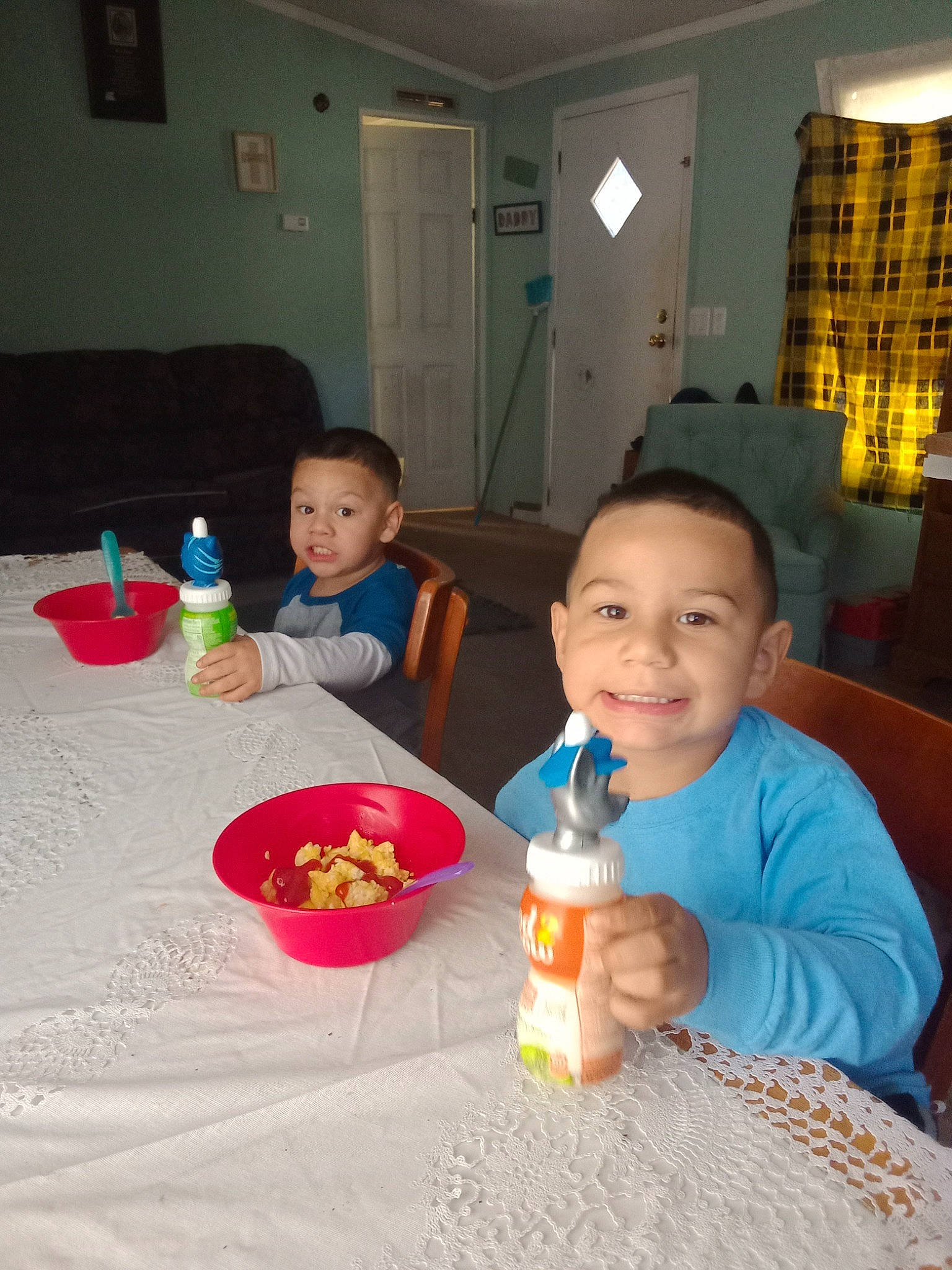 James is registered to the contest to win money with this photo: baby, bottle, chair, child, door, drinkware, event, flooring, fun, joy, person, plastic_bottle, plate, play, room, sharing, smile, table, tableware, toddler