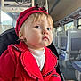toddler, child, red_coat, hat, blue_eyes, train_interior, window, natural_light, portrait, seated, hand, clothing, face, person, travel, public_transport, cute, young_child, indoor, expression