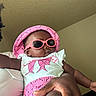 Nyziah is registered to the contest to win money with this photo: accessory, arm, baby, child, clothing, cute, fashion, hand, hat, headwear, holding, indoor, infant, person, pink, portrait, relaxing, skin, sunglasses, wearing
