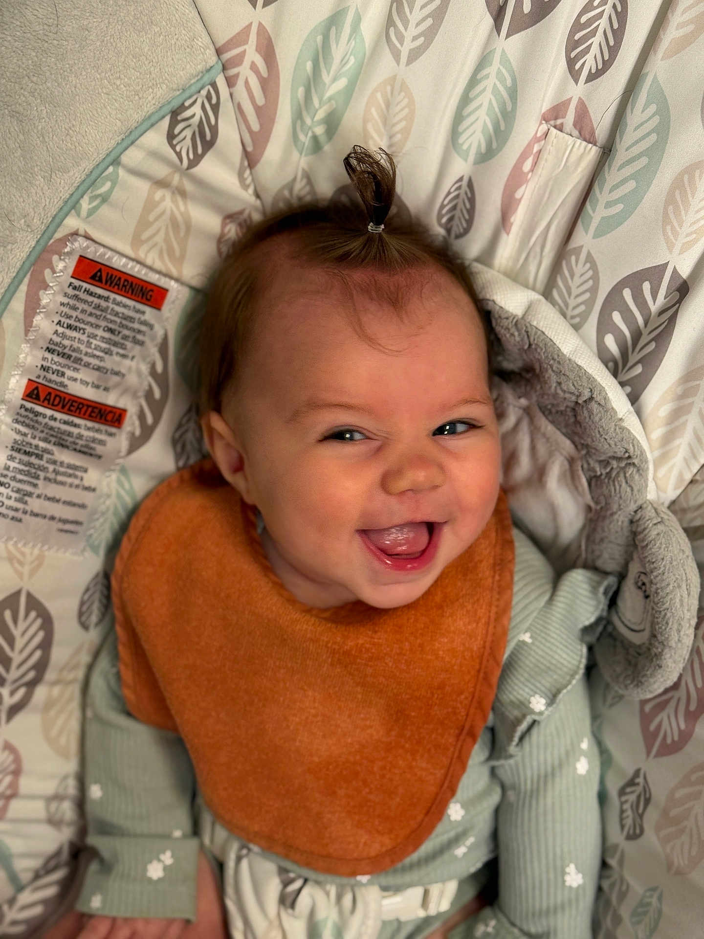 Nikiya is registered to the contest to win money with this photo: baby, smiling, bib, ponytail, green_clothing, baby_seat, leaf_pattern, happy, infant, face, cute, child, soft_toys, indoor, portrait, sitting, cozy, apparel, joyful, expression