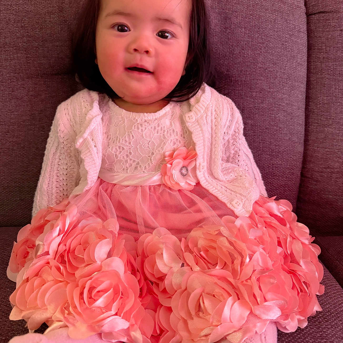 Chanelle is registered to the contest to win money with this photo: baby, child, couch, cozy, cute, face, fashion, flower_decor, girl, happy, indoor, knitted_cardigan, long_hair, pink_dress, portrait, sitting, smiling, soft_lighting, toddler, young_child