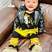Mehrish joined the competition — help win amazing prizes! baby, smiling, leather_jacket, gold_bow, black_clothing, yellow_clothing, couch, indoor, footwear, happy, child, sitting, portrait, cute, fashion, baby_shoes, headband, person, seat, home