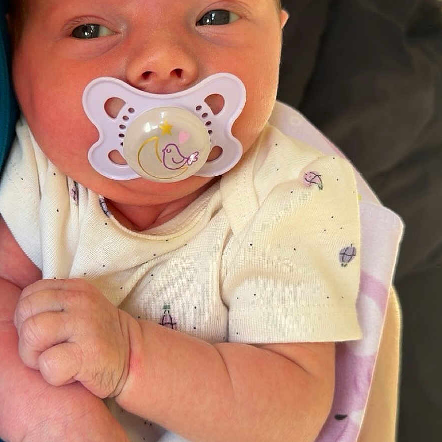 Raylynn is registered to the contest to win money with this photo: baby, pacifier, blanket, hand, nail_polish, infant, cute, skin, clothing, person, newborn, portrait, closeup, sleepwear, holding, pink, purple, white, pattern, soft