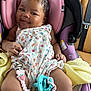 Odyssey is registered to the contest to win money with this photo: baby, smiling, car_seat, pink, purple, floral_onesie, pacifier, strawberry_clip, yellow_blanket, infant, cute, happy, child, seatbelt, indoors, portrait, skin, hand, face, comfort