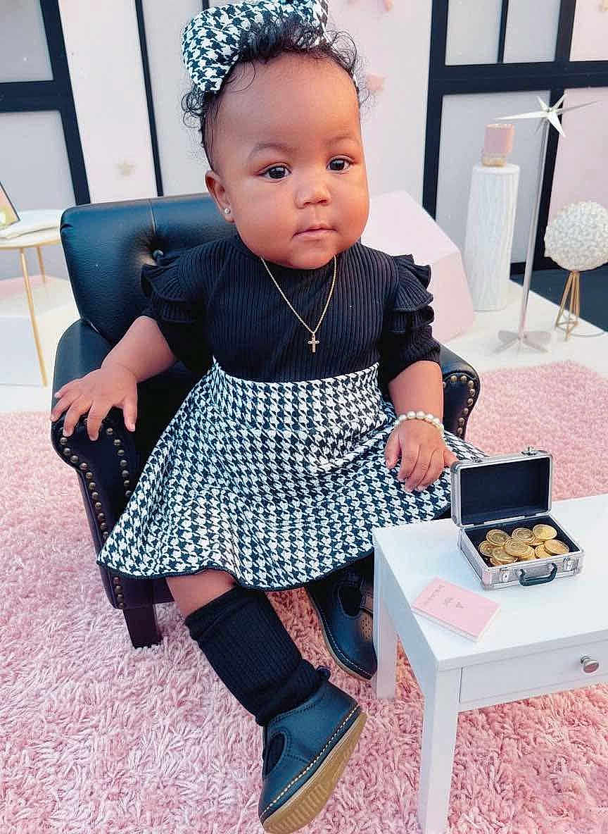 Odyssey is registered to the contest to win money with this photo: accessories, armchair, baby, black_clothing, bow, bracelet, briefcase, carpet, child, coins, cute, fashion, houndstooth, indoor, necklace, portrait, shoes, sock, table, toddler