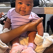 Odyssey joined the competition — help win amazing prizes! baby, infant, child, person, arm, hand, clothing, onesie, booties, pink, lavender, cute, smiling, indoor, blanket, holding, furniture, face, skin, happy