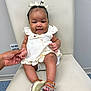 Odyssey joined the competition — help win amazing prizes! baby, child, smiling, dress, sandals, hand, chair, indoor, person, cute, holding_hand, happy, skin, footwear, infant, seated, white_dress, ribbons, face, portrait