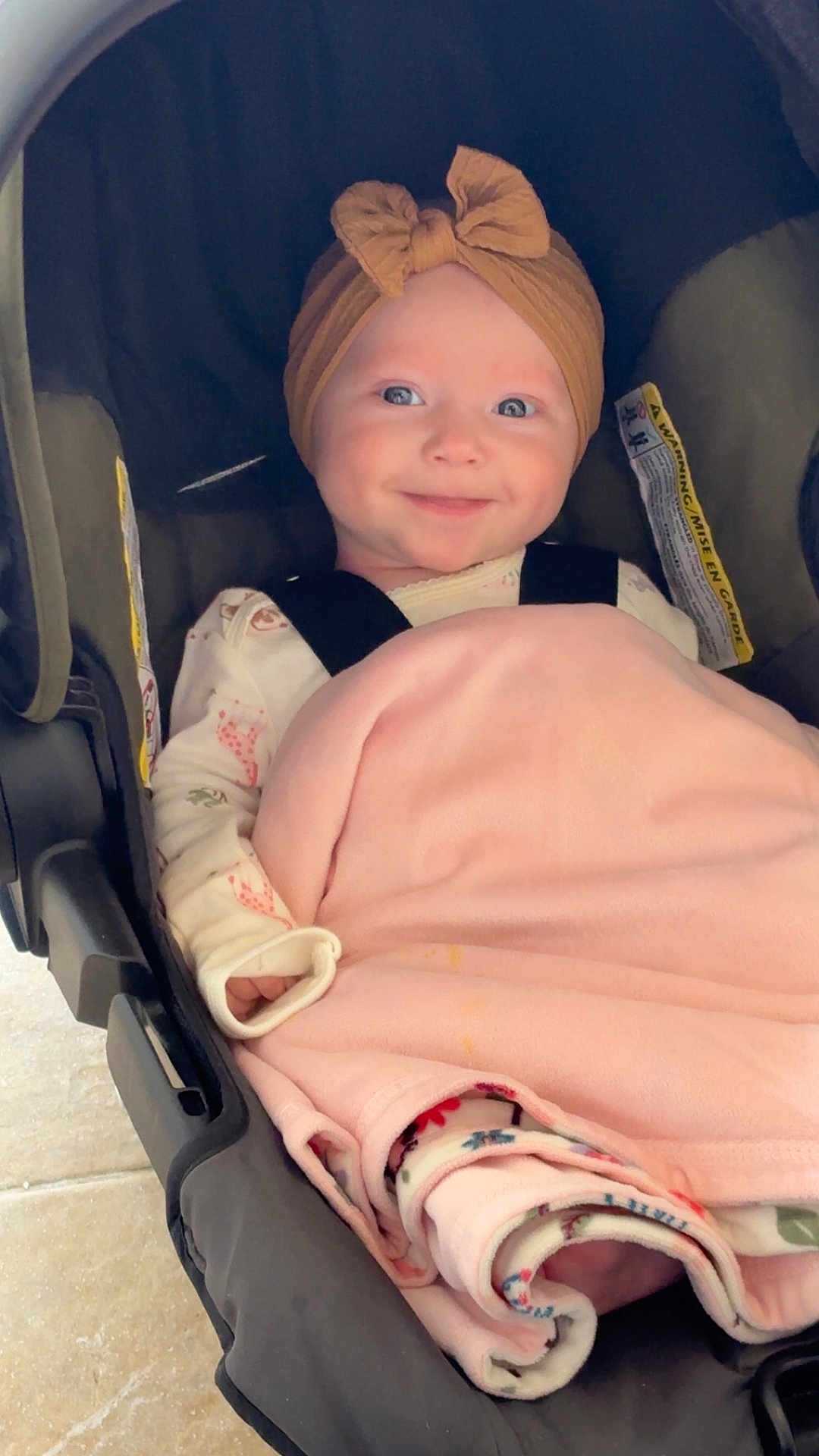 Freyja is registered to the contest to win money with this photo: baby, child, car_seat, blanket, headwrap, smile, pajamas, infant, cute, indoors, seatbelt, comfort, wrapped, young_child, portrait, happy, sitting, face, clothing, toddler