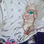 Freyja joined the competition — help win amazing prizes! baby, infant, pacifier, blanket, milestone_blanket, hat, clothing, pink, floral, pattern, laying_down, indoors, cute, child, person, soft, warm, fabric, sleepwear, newborn