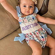 Braelyn joined the competition — help win amazing prizes! baby, beige, blue_checkered_bow, child, couch, cute, floral_pattern, flower_headband, footwear, girl, happy, headband, indoor, person, portrait, romper, sitting, skin, smiling, young