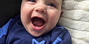 Luca George joined the competition — help win amazing prizes! baby, smiling, happy, infant, face, blue_clothing, star_pattern, blanket, closeup, cute, child, young, portrait, soft_texture, cozy, indoor, person, head, joy, expression