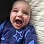 baby, smiling, happy, infant, face, blue_clothing, star_pattern, blanket, closeup, cute, child, young, portrait, soft_texture, cozy, indoor, person, head, joy, expression