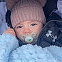 Luca George is registered to the contest to win money with this photo: baby, child, pacifier, hat, knit_hat, pom_poms, blanket, blue_blanket, jacket, winter_clothing, under_armour_logo, face, eyes, cute, cozy, infant, cold_weather, closeup, portrait, warm