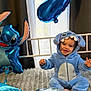 Theo participe au concours pour gagner de l'argent avec cette photo : balloon, bed, blanket, blue_onesie, celebration, child, costume, curtain, cute, footwear_free, happy, indoors, number_balloon, party, person, plush, smiling, stitch, toddler, window