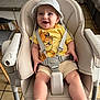 baby, high_chair, smiling, hat, yellow_shirt, lion_king, straps, happy, indoors, kitchen, tiled_floor, furniture, child, person, cute, clothing, seat, sock, sitting, portrait